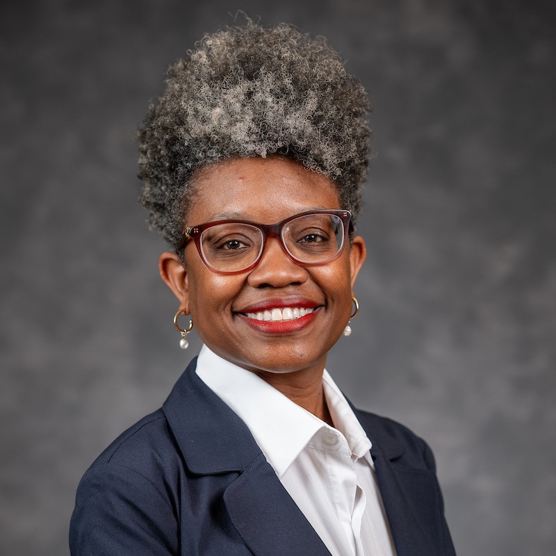 Woman with tall hair, earrings and glasses smiling